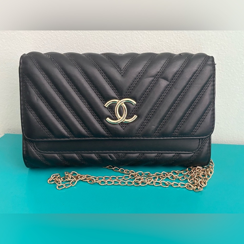 Black quilted purse with gold chain shoulder strap.